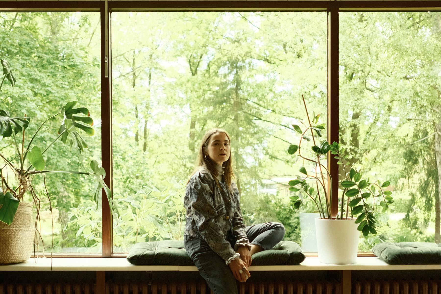Woman sitting on a window bench in green light