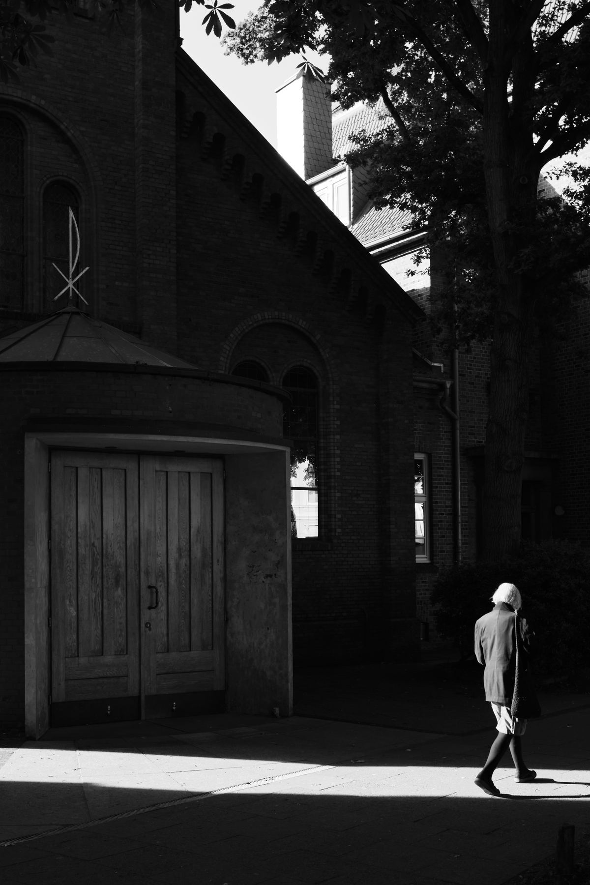 Man walking through hard shadows beside a church