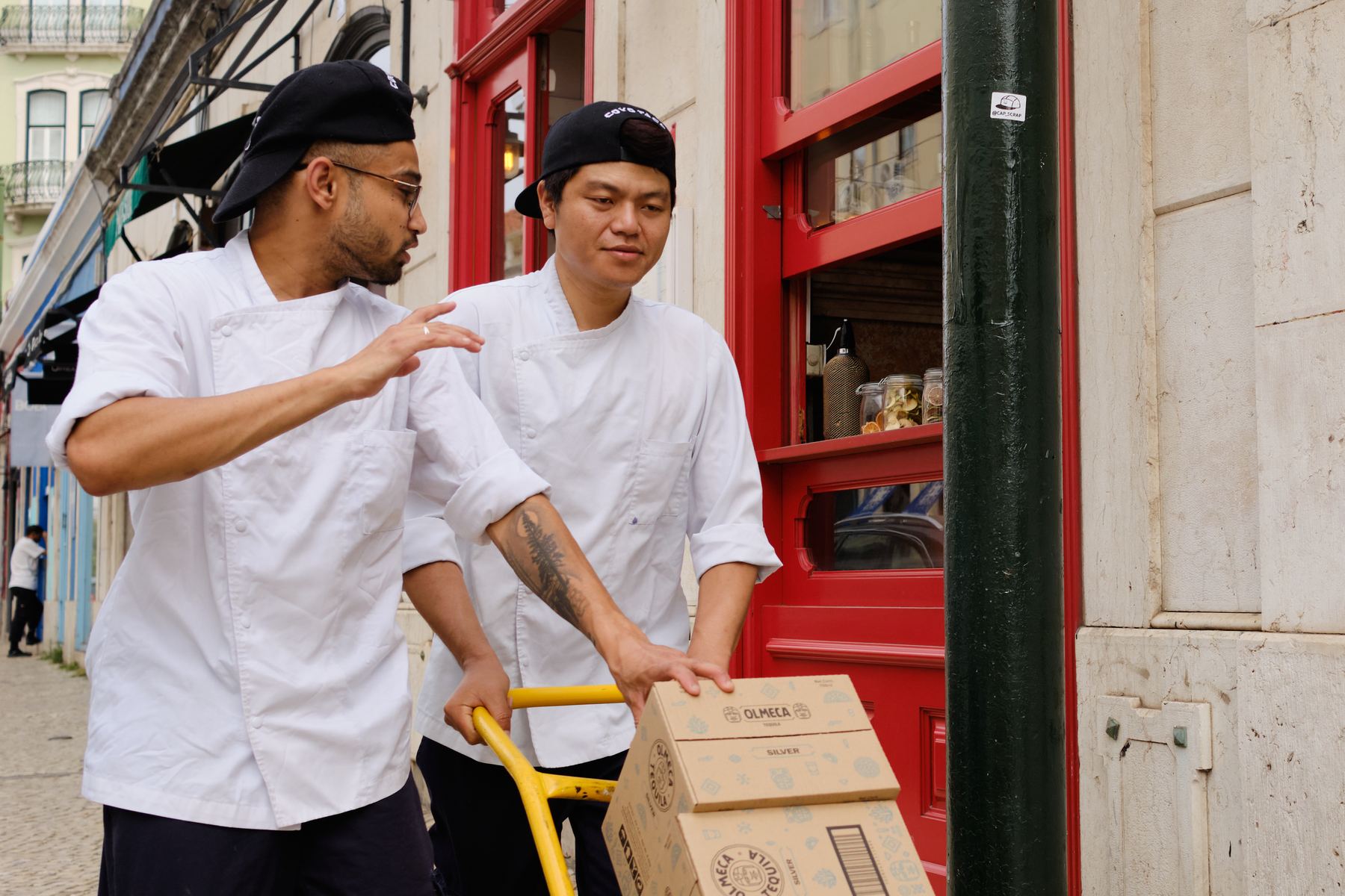 Two cooks with a hand truck in a Lisbon street